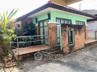 Charming single-story house with brick facade and lush greenery