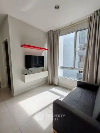 Modern living room with sleek TV setup and large window for natural light.