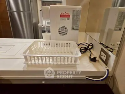 Modern kitchen counter with appliance and basket, featuring sleek design and convenient power outlet.