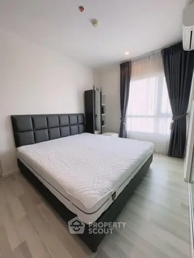 Spacious bedroom with modern decor and large window for natural light.