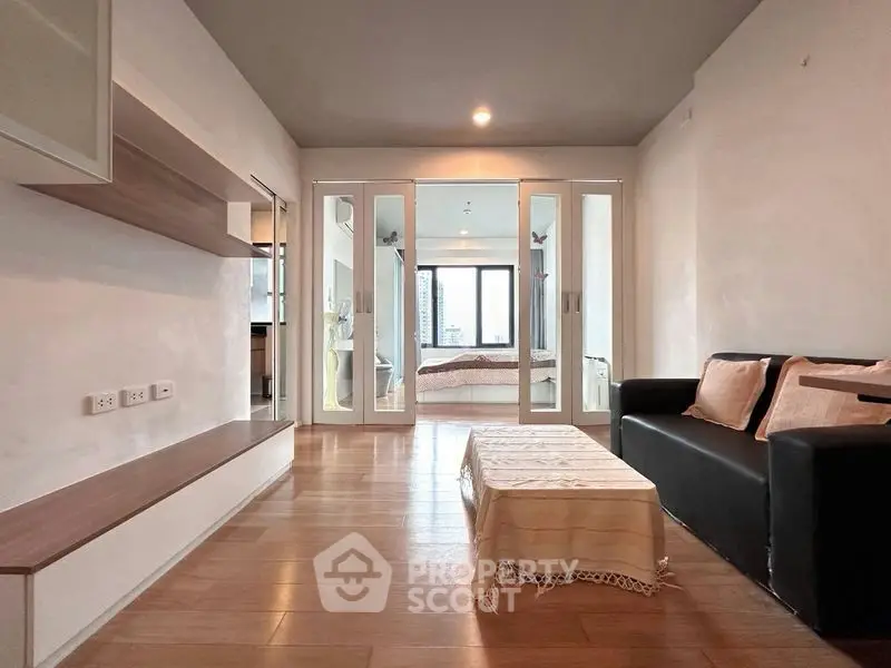 Modern living room with wooden flooring and cozy seating area in a stylish apartment.