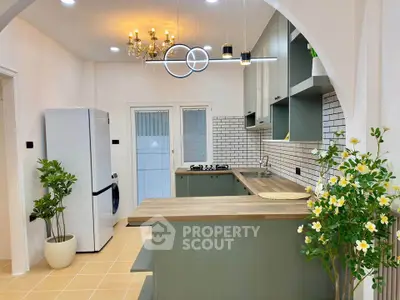 Stylish modern kitchen with elegant lighting and green cabinetry, featuring a spacious layout and sleek appliances.