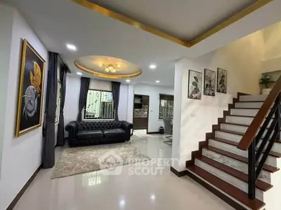 Elegant living room with modern decor and staircase, featuring a stylish black sofa and artistic wall paintings.
