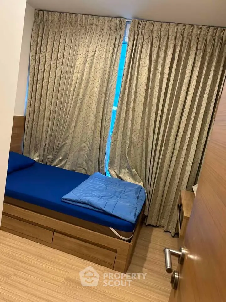 Cozy bedroom with wooden flooring and elegant curtains, featuring a comfortable bed and modern design.