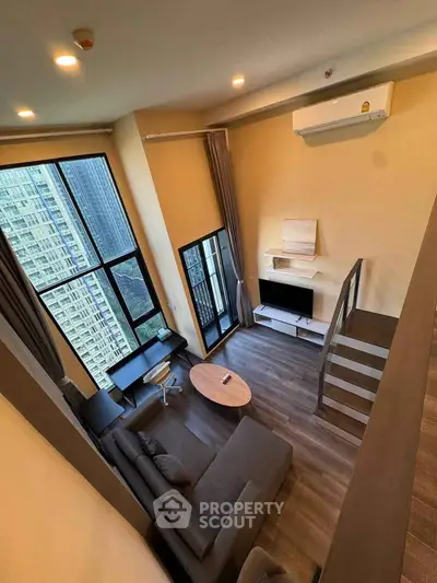 Modern loft-style living room with high ceiling and large windows in urban apartment.