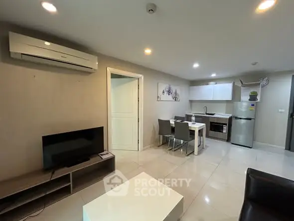 Modern living room with open kitchen, featuring sleek furniture and contemporary design.