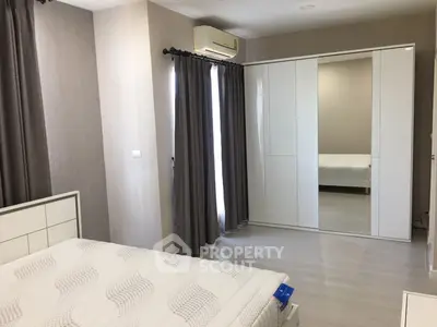 Spacious and modern bedroom with large mirrored wardrobe and elegant neutral tones, featuring air conditioning and ample natural light.