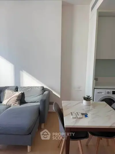 Modern living room with cozy sofa and dining area, featuring a washing machine in a compact space.