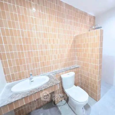 Modern bathroom with orange tiled walls and sleek fixtures