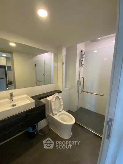 Modern bathroom with sleek fixtures and glass shower enclosure in a contemporary apartment.