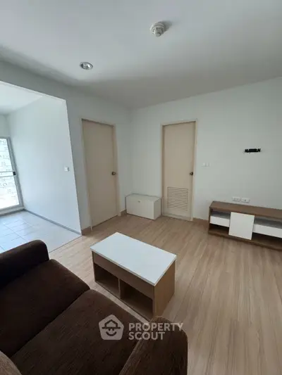 Modern living room with wooden flooring and minimalist furniture in a bright apartment.