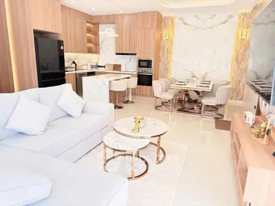 Luxurious open-plan living room with modern kitchen and elegant dining area, featuring marble accents and stylish decor.