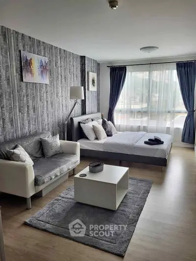Modern bedroom with stylish decor and natural light, featuring a cozy seating area.