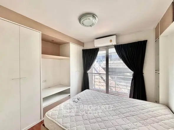 Bright bedroom with large window, built-in wardrobe, and air conditioning unit.