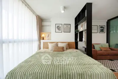 Modern bedroom with stylish decor and cozy seating area, featuring a large window with sheer curtains.