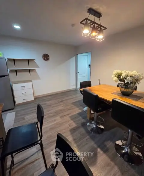 Modern dining area with stylish lighting and wooden table in cozy apartment.