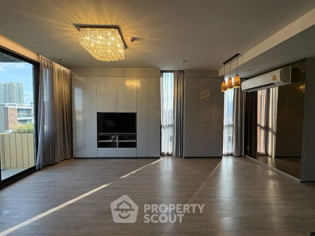 Spacious modern living room with elegant lighting and large windows offering city views.