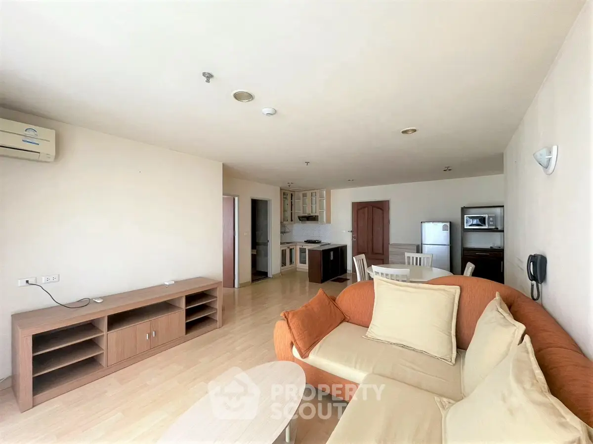 Spacious living room with modern furniture and open kitchen layout in a cozy apartment.