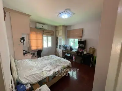 Cozy bedroom with wooden flooring, ample natural light, and functional workspace in a modern home.