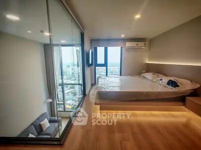 Modern bedroom with glass wall and city view, featuring sleek design and cozy ambiance.
