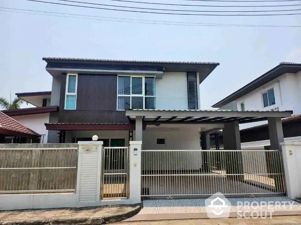 Modern two-story house with gated driveway and contemporary design in suburban neighborhood.