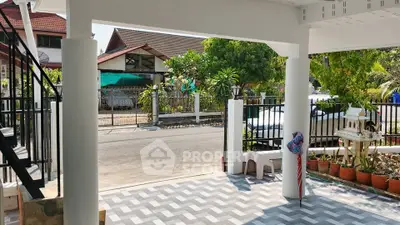 Charming residential entrance with tiled patio and lush greenery in a peaceful neighborhood.