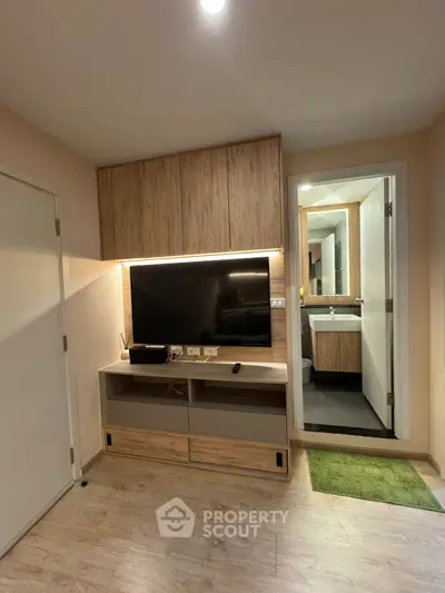 Modern living room with sleek wooden TV unit and adjacent bathroom view.