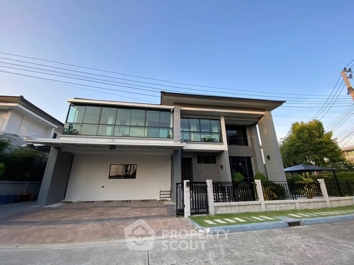 Modern two-story house with large windows and spacious driveway in a serene neighborhood.