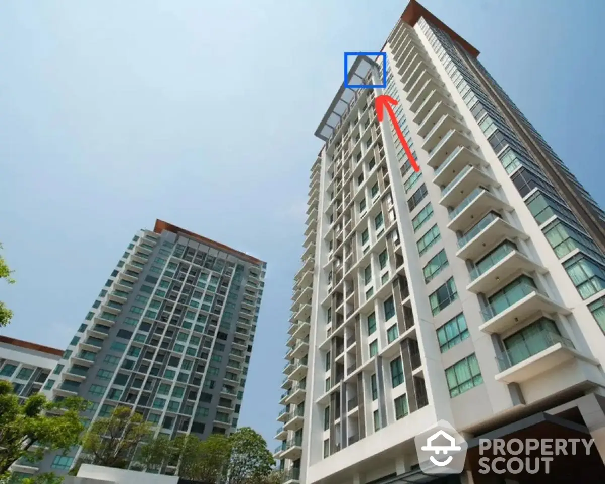 Modern high-rise residential building with balconies and clear sky view.