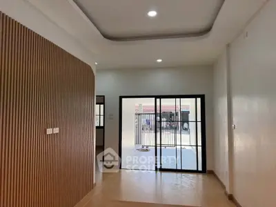Modern interior with sliding glass doors and stylish wooden paneling, leading to a spacious outdoor area.