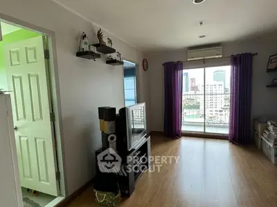 Spacious living room with hardwood floors, ample natural light, and a charming city view through large windows, complemented by elegant purple drapes.