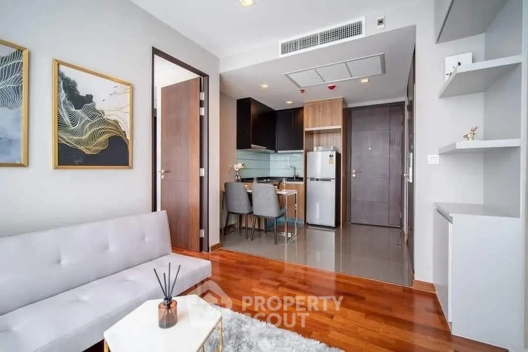 Modern living room with open kitchen, wooden flooring, and stylish decor in a contemporary apartment.