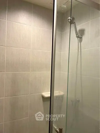 Modern bathroom with glass shower enclosure and tiled walls.