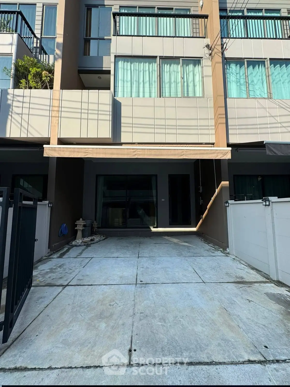 Modern townhouse exterior with driveway and balcony, ideal urban living space.