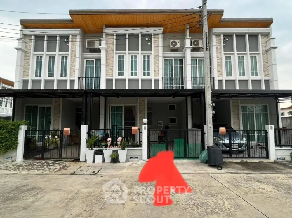 Modern townhouse exterior with gated entrance and balcony, ideal for urban living.