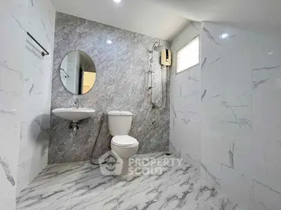 Modern bathroom with marble tiles, round mirror, and sleek fixtures