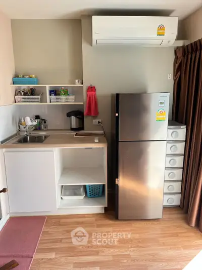 Cozy kitchen with modern fridge and air conditioning, featuring open shelving and wooden flooring.
