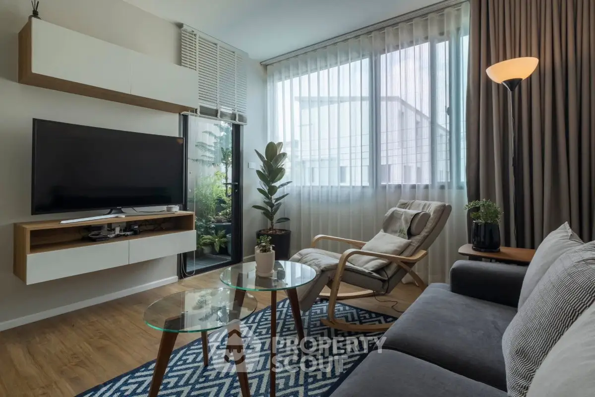 Modern living room with stylish furniture and large window offering natural light.