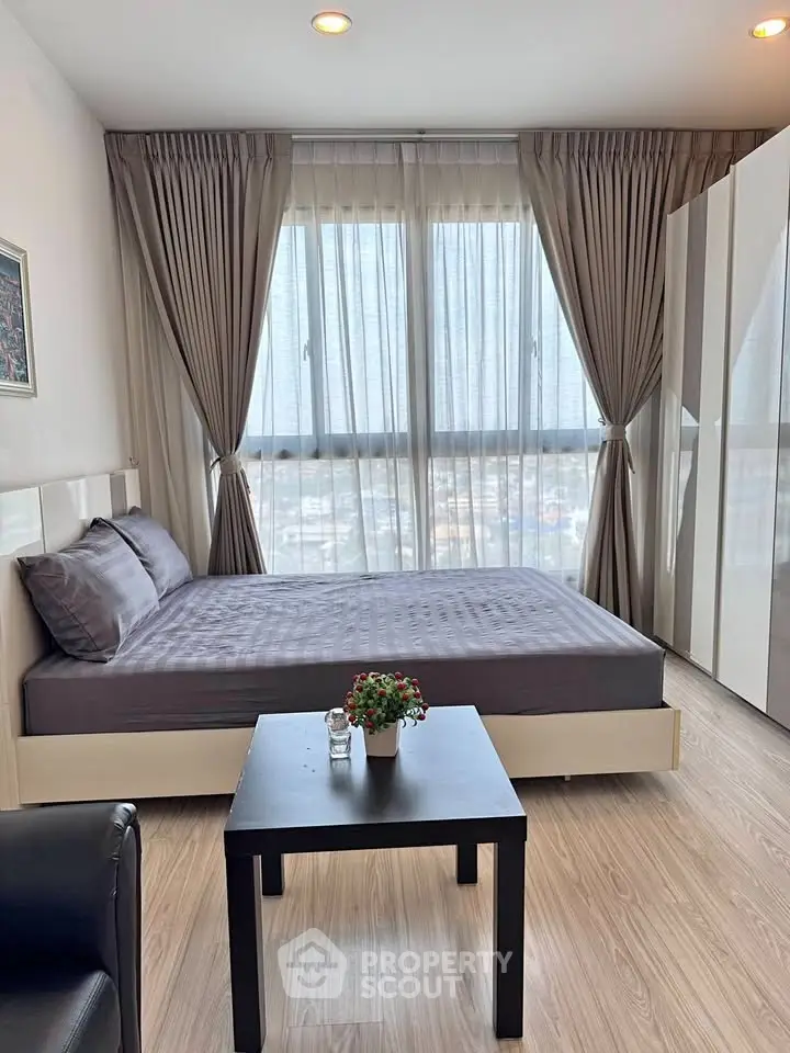 Modern bedroom with large windows and stylish decor in a high-rise apartment.