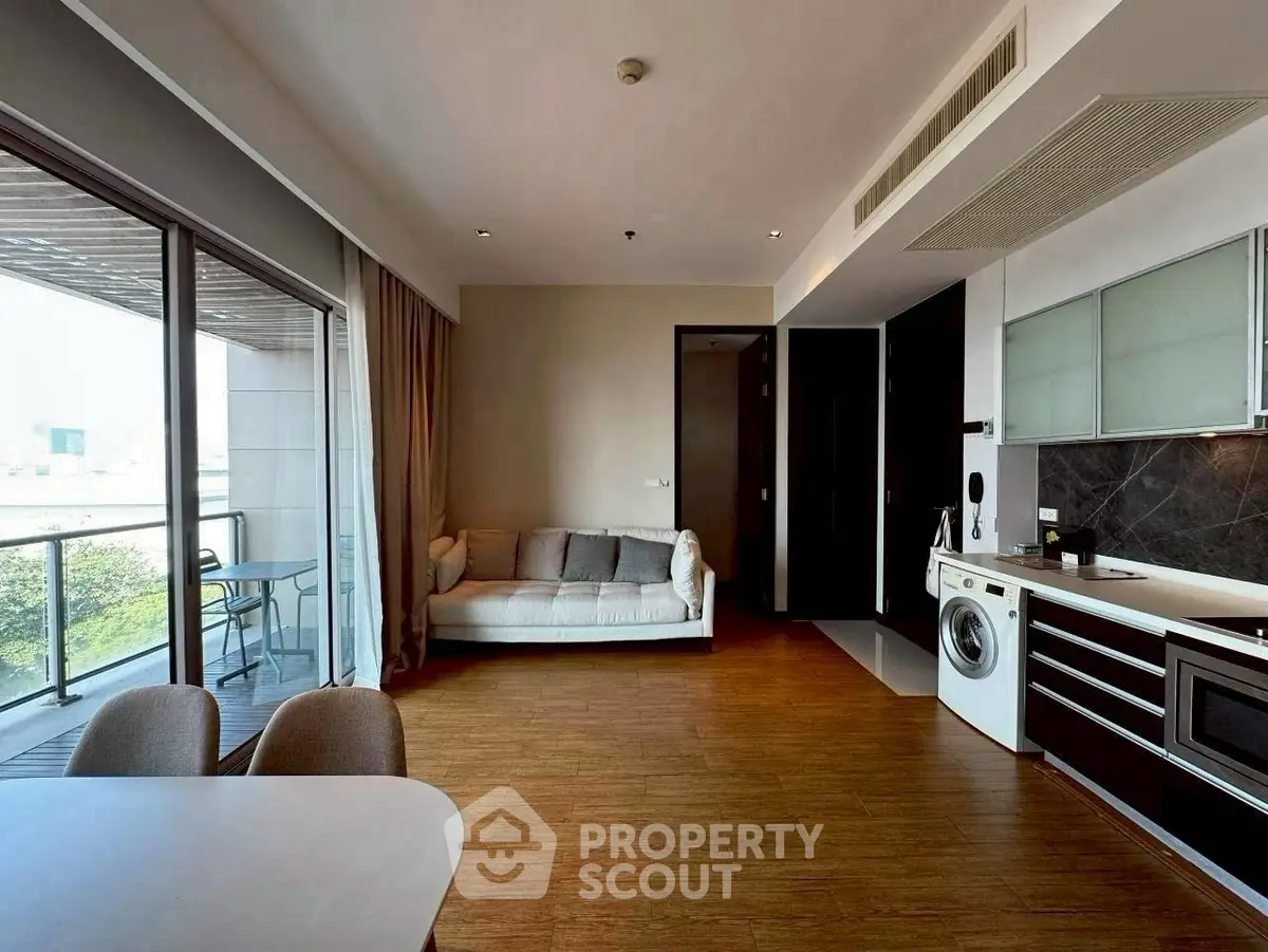 Modern living room with balcony, featuring a washing machine and sleek kitchen design.