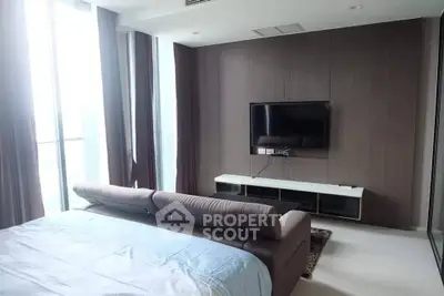 Modern bedroom with sleek TV setup and large windows offering natural light.