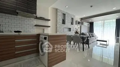 Modern open-plan living room with sleek kitchen and dining area, featuring stylish decor and natural light.