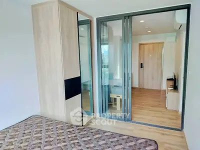 Modern bedroom with wooden flooring and mirrored wardrobe in a stylish apartment.