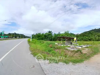 Scenic roadside land plot with lush greenery and potential for development.