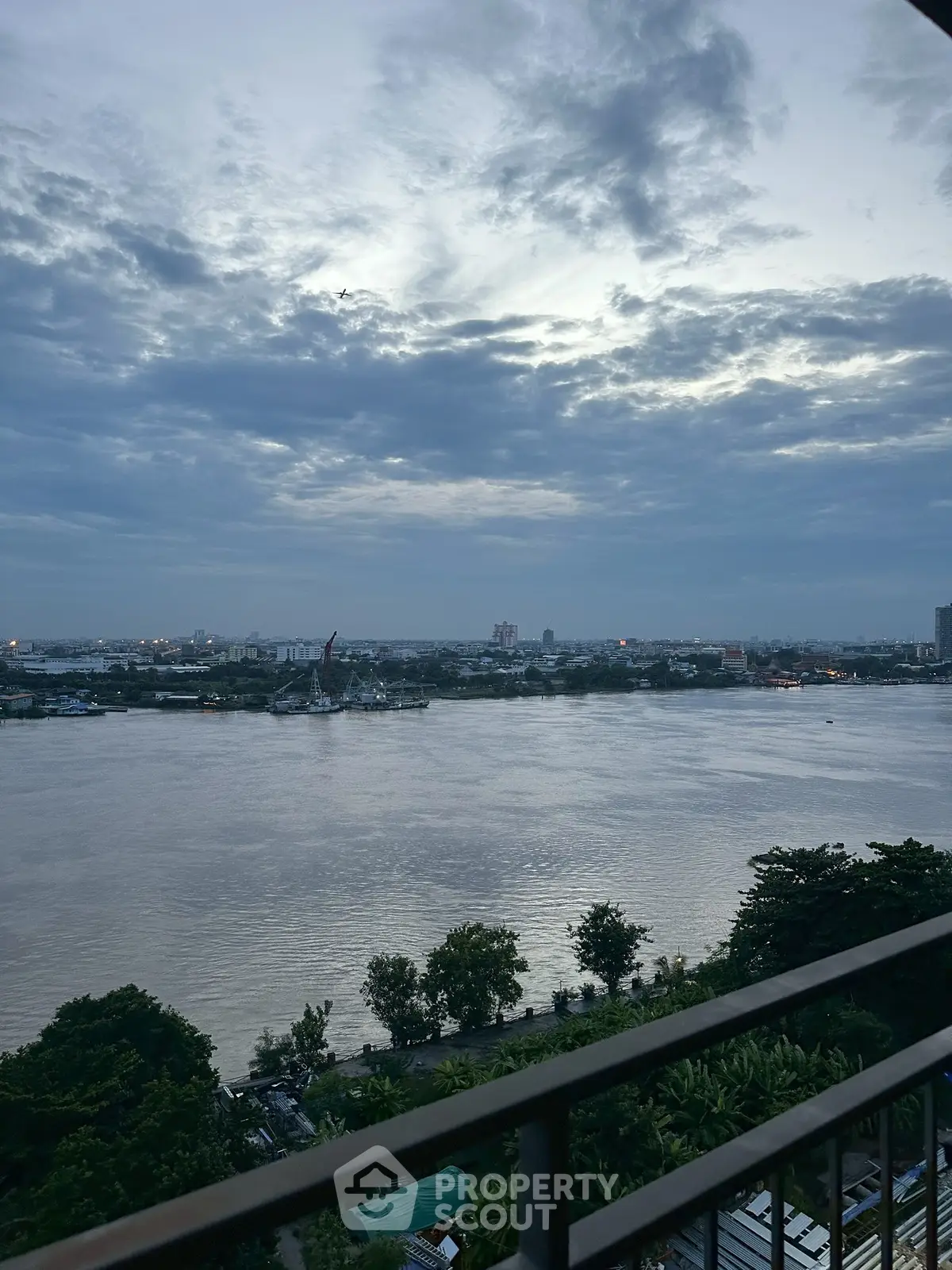 Stunning river view from a high-rise balcony at dusk, perfect for serene living.