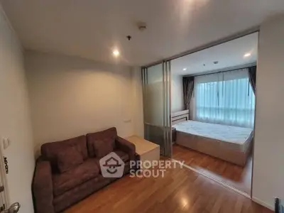 Cozy apartment with sliding doors separating living room and bedroom, featuring wooden floors.