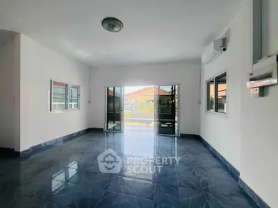 Spacious living room with glossy blue tile flooring and large windows for natural light.