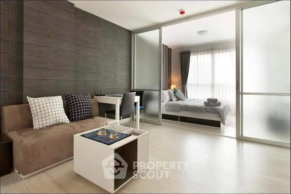 Modern apartment with open living room and bedroom, featuring sleek design and natural light.