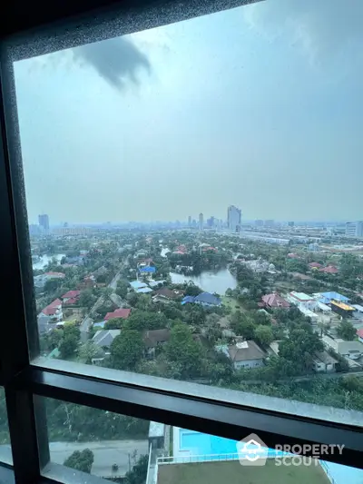 Expansive high-rise view from a modern apartment showcasing a serene urban panorama with lush greenery and distant city skyline.