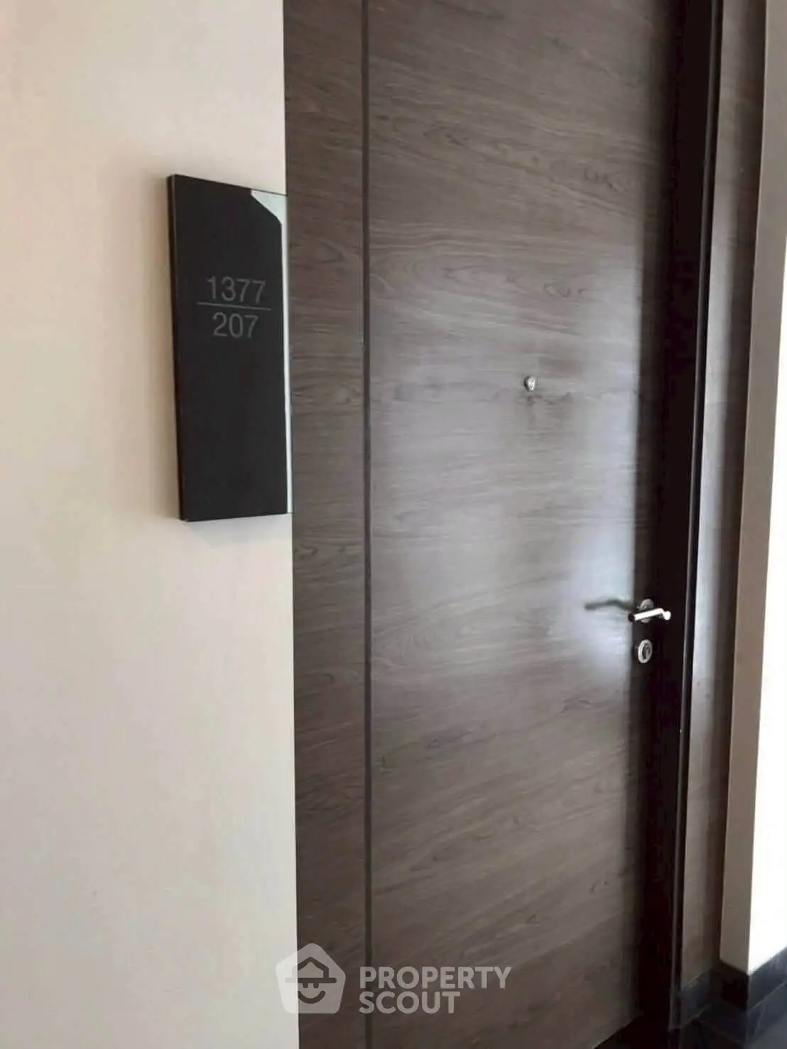 Modern apartment entrance with sleek wooden door and room number signage.